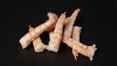 Chefs hand with gloves dropping fresh peeled shrimp tails on a black surface Video stock 331303158