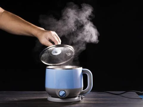 The chef's hand opens the lid of the hot soup pot. with smoke on black backgr Stock Photos