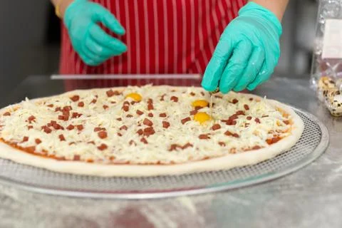 Chefs hand preparing pizza on kitchen table top with quail egg, Stock Photos