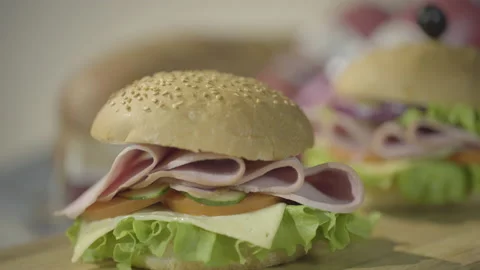 Chef's hand put black olive into hamburger with salad and beef. Macro shot, 4k 動画素材 143654762