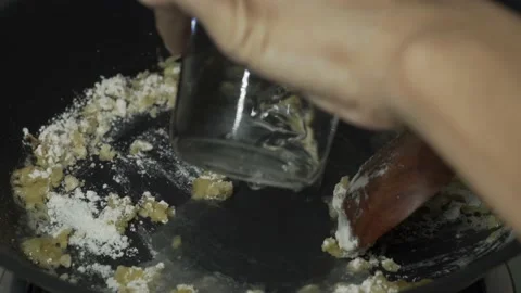 Chef's hand put a little bit water to a pan Stock Footage 133700417