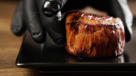 Chef's hand puts filet mignon steak on a plate. Stock Footage 126220454