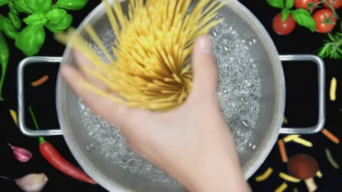 Chef's Hand Puts Spaghetti Pasta into Pot with Boiling Water - Top View Stock Footage 168702172
