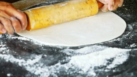 The chef's hand is rolling pizza dough into a flatten circle shape Stock Footage 221737941