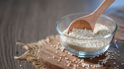 Chef's hand is scooping white sesame seeds in a glass bowl 스톡 동영상 131421082