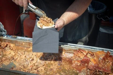 Chef's hand serving delicious pulled pork in a sandwich bun in a street marke Stock Photos