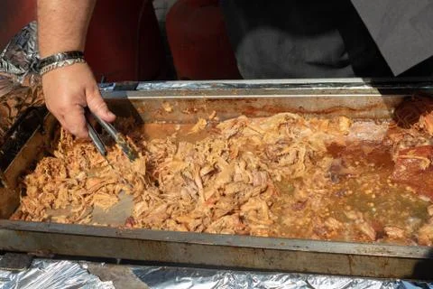 Chef's hand serving delicious pulled pork in a sandwich bun in a street marke Stock Photos