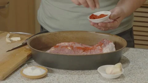 Chef's hand sprinkles red pepper on a piece of raw meat stuffed with garlic Stock Footage 256427184