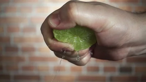 Chef's hand squeezes of green lime, close-up slow motion hd video Stock Footage 72183665