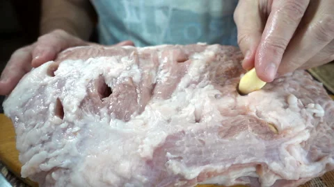Chef's hand stuffing garlic a piece of raw meat in slow motion Stock Footage 129333872