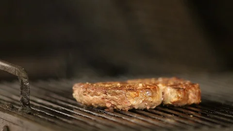 The chef's hand turns the beef steak on the grill with pliers.close-up Stock Footage 115659231
