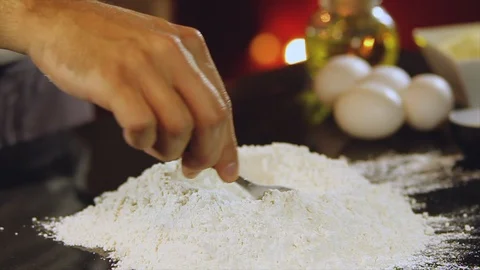 Chef's hand using a fork to make a hole in the mound of flour so he can start pr Stock Footage 100647734
