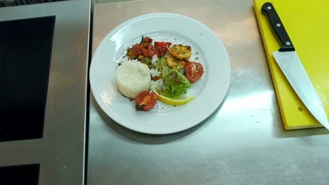 Chef's hands adding sauce to the rice with vegetables on a plate Vidéo 72324276