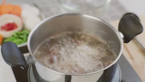 Chef's hands are putting pork ribs in a pot of boiling water in the kitchen. Stock Footage 242343702