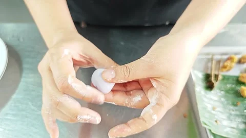 A chef's hands are shaping purple dough for a traditional Thai dessert. Video stock 343208838