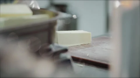 The chef's hands in blue gloves cut a piece of butter with a knife Video stock 149147622
