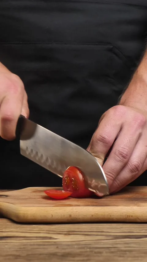 Chef's hands cut fresh tomato with a knife on a wooden board. A chef without a Stock Footage 304154186