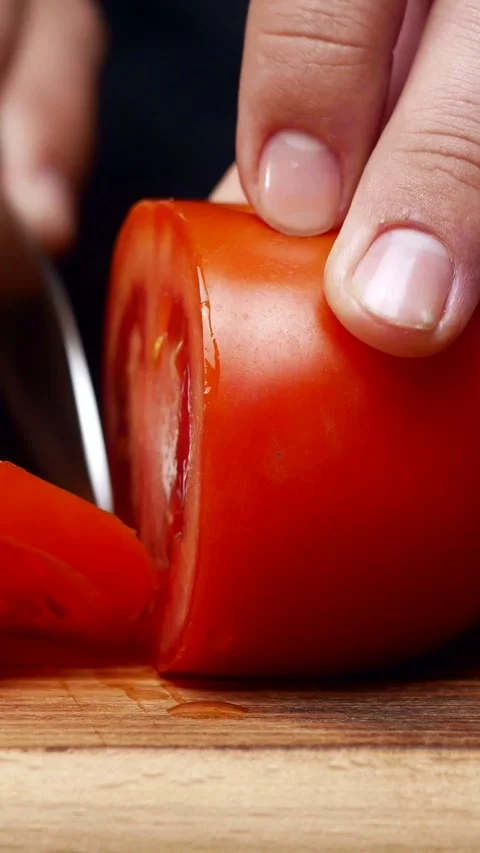 Chef's hands cut fresh tomato with a knife on a wooden board. A chef without a Stock Footage 304437617