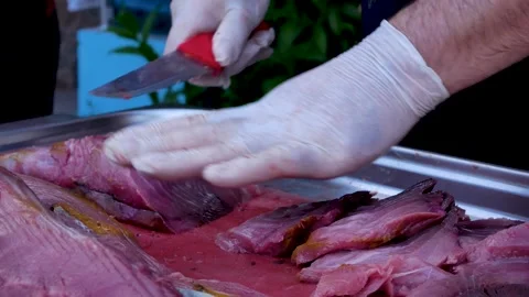 The chef's hands cut a large piece of fish meat. Grilling meat. Picnic in nature Stock Footage 253591515