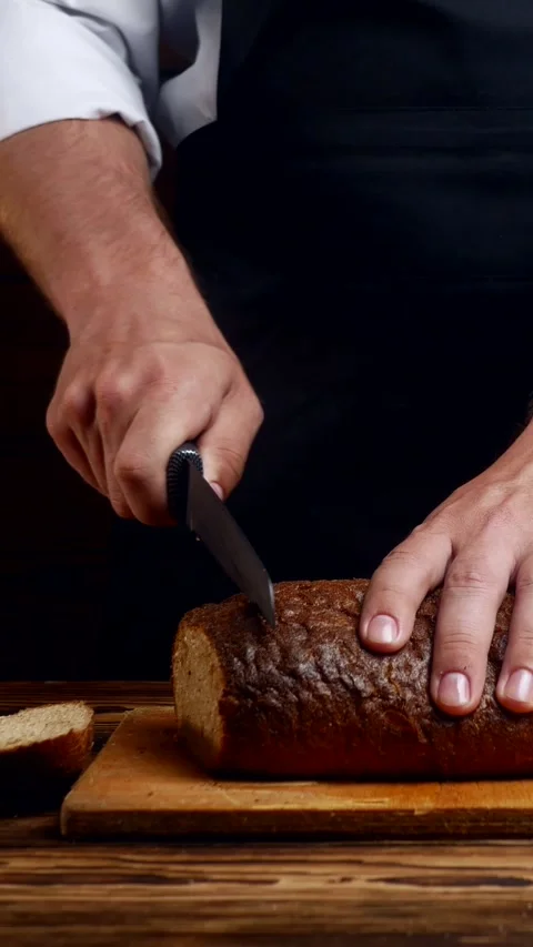 Chef's hands cutting bread with a knife in the kitchen Stock Footage 304437665