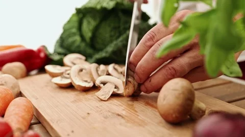 Chef's hands cutting fresh champignon mushrooms on a wooden board with a large 스톡 동영상 202137788
