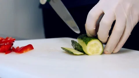 Chef's hands cutting a fresh cucumber. Hands in gloves cut cucumbers Stock Footage 163632493