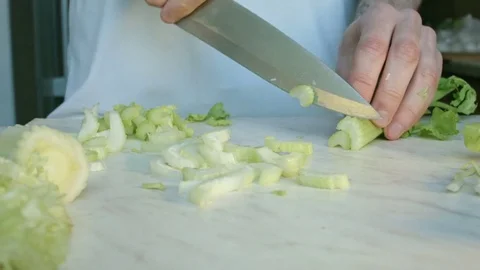 Chefs hands cutting a fresh green celery leaf. 動画素材 80255304