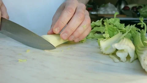 Chefs hands cutting a fresh green celery leaf. 動画素材 80255339