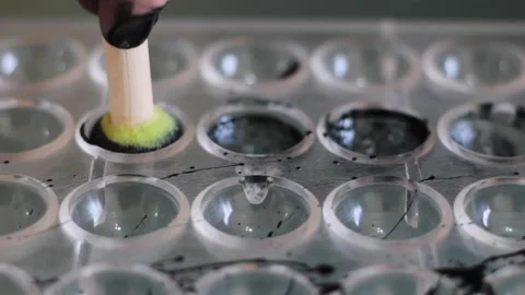 Chef's hands decorates round chocolate molds with brush 動画素材 230701031