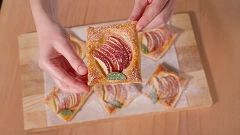Chef's hands demonstrate puff pastries with apples and powdered sugar Stock Footage 267011159