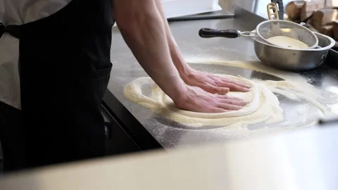 The chef's hands form a round pizza base from the dough with his hands. Stock Footage 307388828