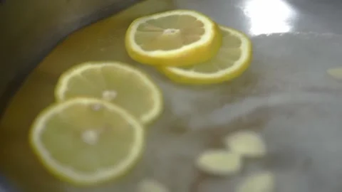 Chef's hands in gloves throw lemon slices into a pan with garlic. HD Stock Footage 141932060