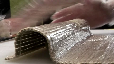 Chef's hands in gloves wrapping sushi rolls in the kitchen and cutting Stock Footage 285248537