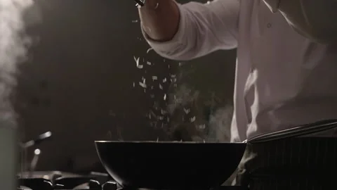 Chef's hands grating parmesan cheese over a hot, steaming pan Stock Footage 335459570