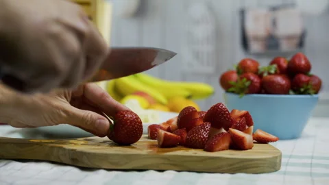 Chef's hands holding sharp knife and slicing up strawberries on cutting board - Stock Footage 341225035