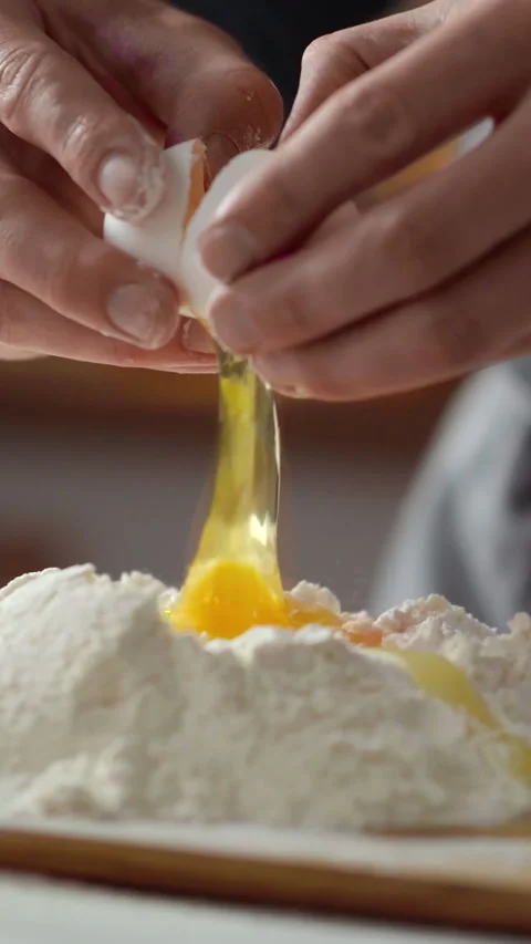 Chefs hands knead dough for baking in cozy kitchen cracking fresh egg into b Stock Footage 338200124