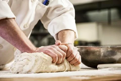 A chef's hands kneading bread dough on a floured worktop. Stock Photos