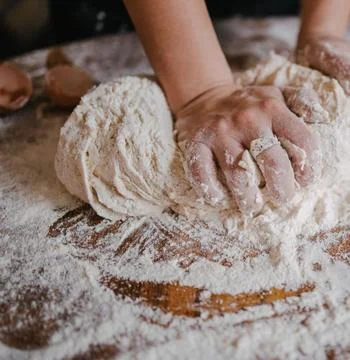Chefs Hands Kneading Fresh Bread Dough on a Floured Worktop Stock Photos