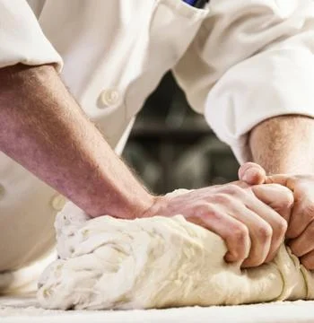 Chefs Hands Kneading Fresh Bread Dough on a Floured Worktop Stock Photos