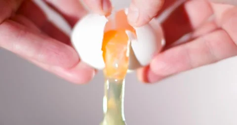 Chef's hands open a cracked egg in half and the white and yolk falls down. Stock Footage 262668671