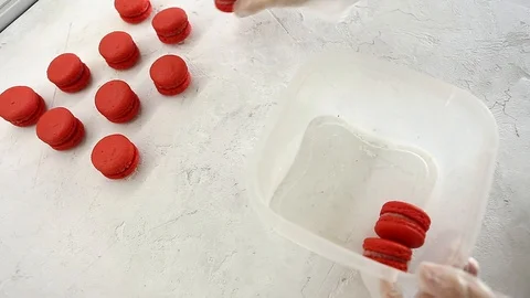 Chefs hands packaging fresh baked red strawberry macaroon into container Vídeos de archivo 129917677