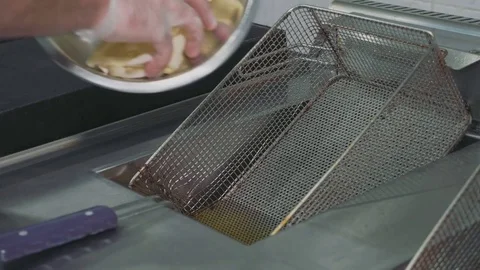 Chef's hands pouring a potato to a deep fryer for cooking french fries Stock Footage