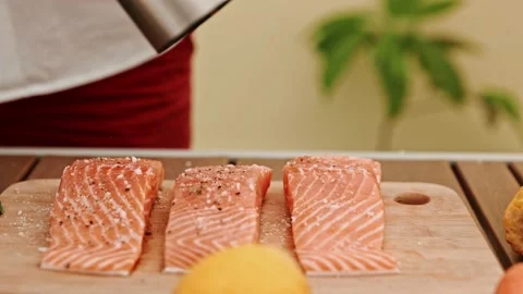The chef's hands prepare salmon fillets, sprinkling with salt ingredients Stock Footage 201139727