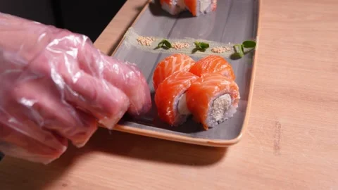 Chef's hands putting rose of ginger pieces on plate of delicious sushi Vídeo Stock 269547435