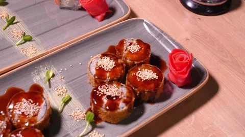 Chef's hands putting rose of ginger pieces on plate of delicious sushi Stock Footage 269547830