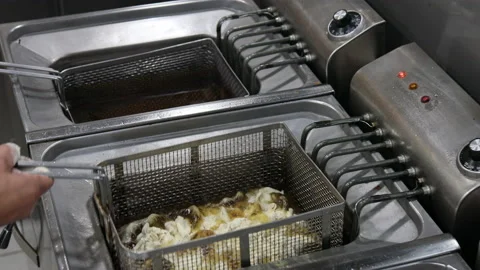 Chef's hands in a restaurant kitchen placing baby squids in a fryer Stock Footage 220947345