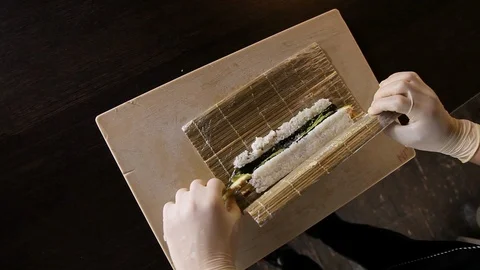 Chef's hands rolling a sushi roll on bamboo mat. Stock Footage 120626683