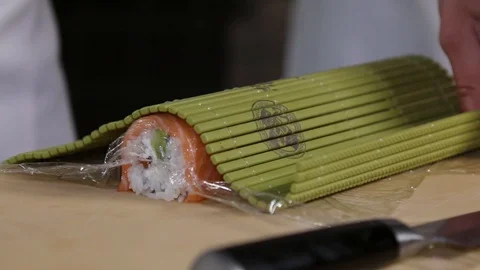 Chef's hands rolling a sushi roll. Sushi making process. Rolls the sushi roll Stock Footage 130117968