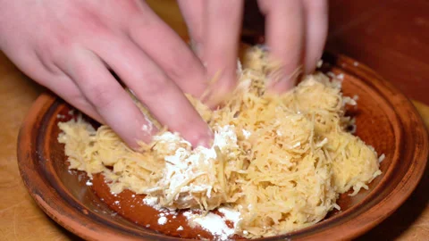 Chef's hands shaking grated raw potatoes with flour Stock Footage 247845274