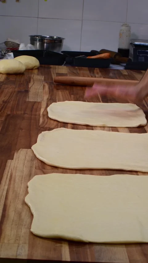 Chef's Hands Skillfully Flattening Dough in a Rustic Kitchen Setting Stock Footage 332421132